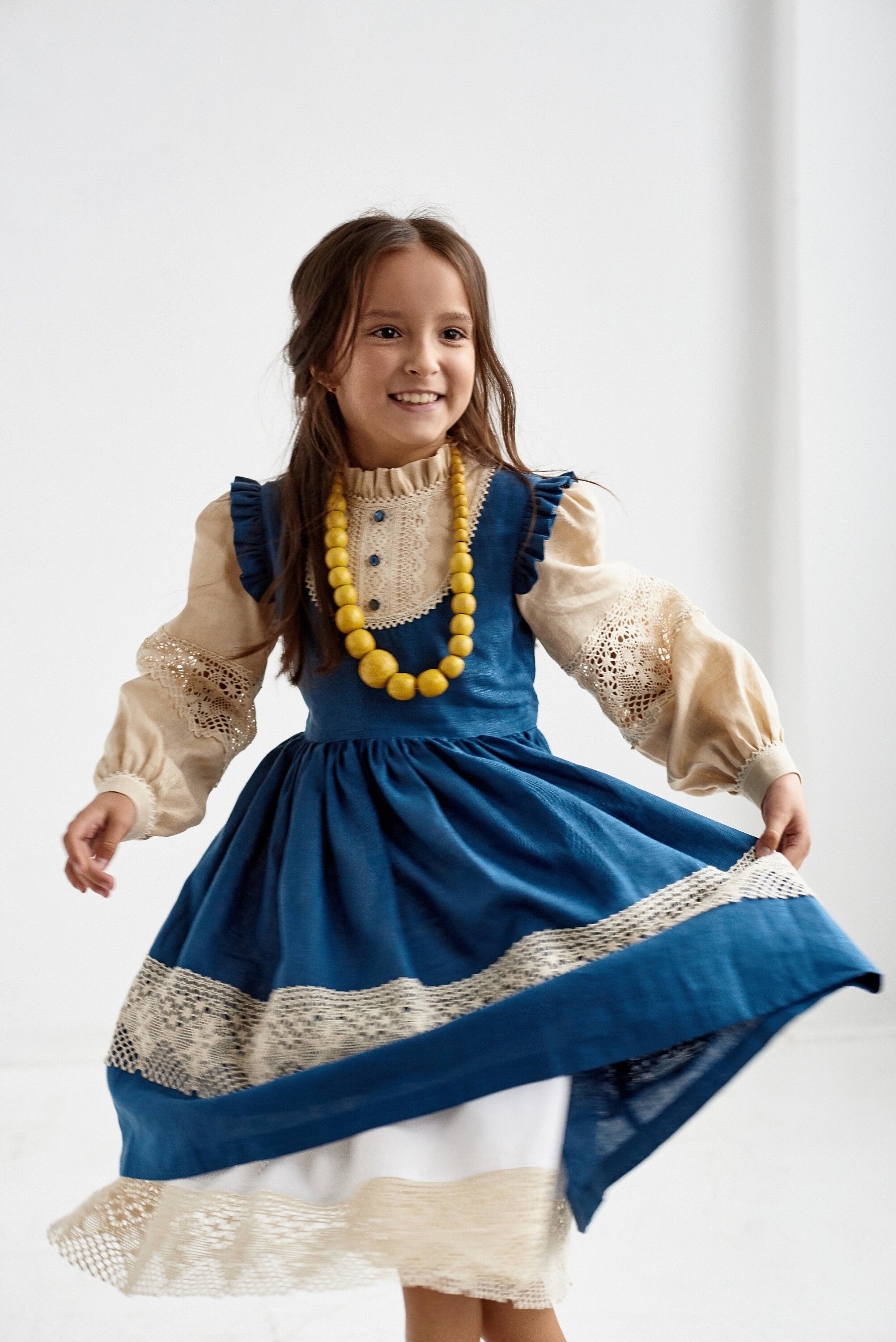 Alt Tag: Girl wearing a blue Ukrainian linen Vyshyvanka dress with lace trim and long puff sleeves, perfect for special occasions.