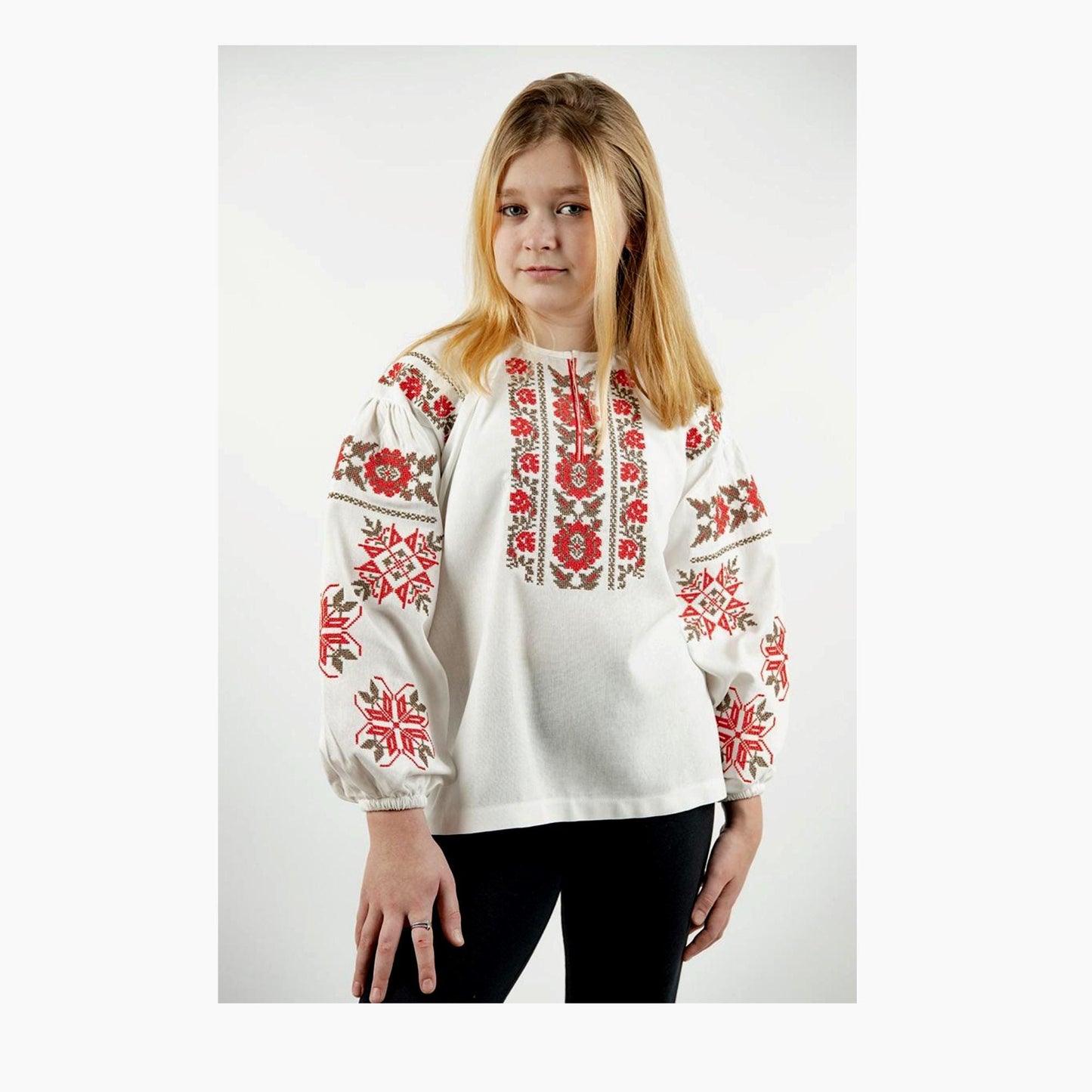 Girl wearing a Ukrainian linen embroidered shirt in milk color with red floral ornament, suitable for ages 5-16.