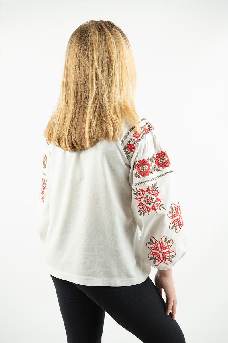 Girl wearing Ukrainian linen shirt with red floral embroidery, back view. Milk color blouse for girls, sizes 5–16 years.