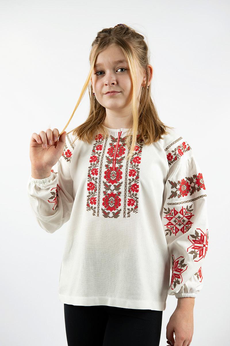 Girl wearing milk-colored Ukrainian linen embroidered shirt with ethnic floral design, suitable for ages 5-16, showcasing cultural fashion.
