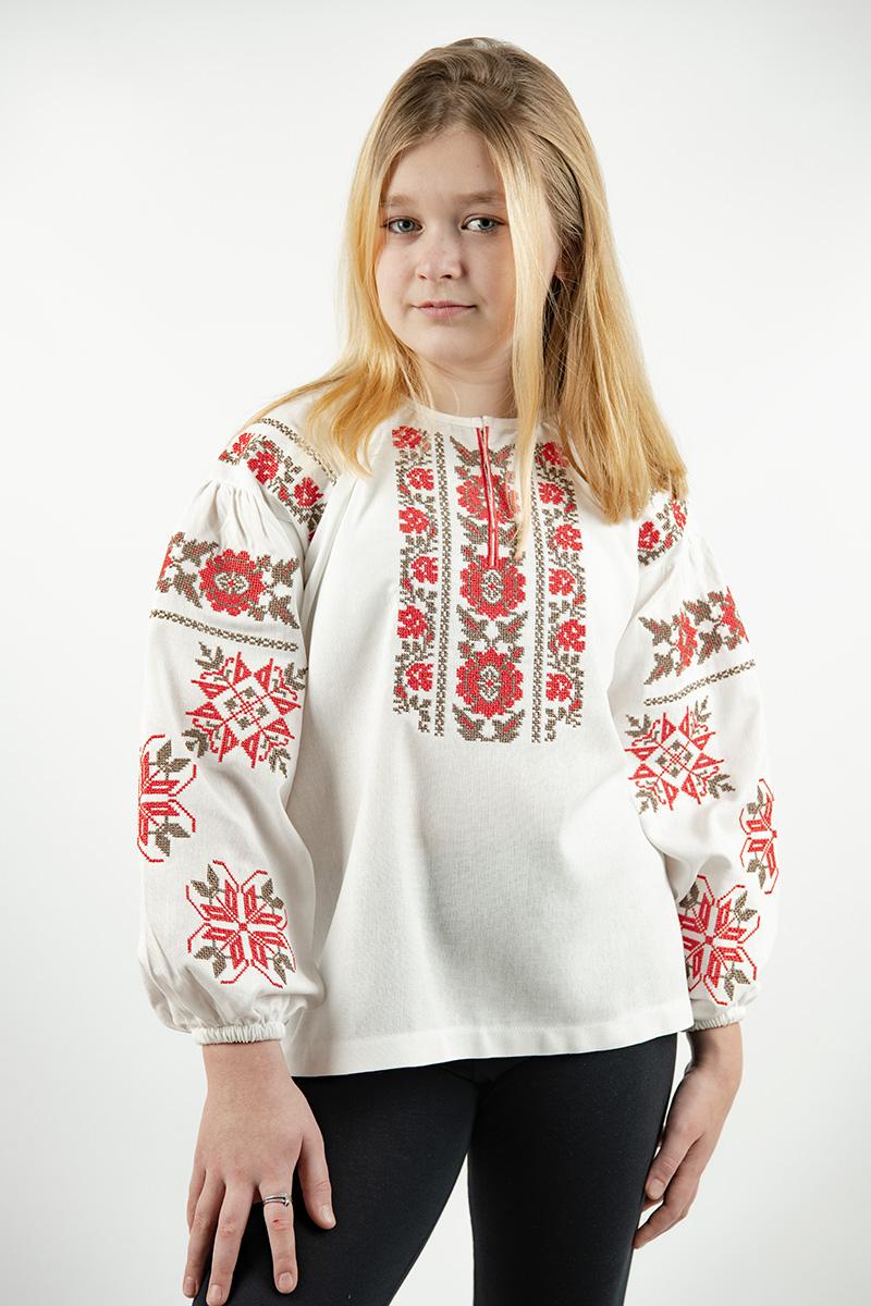 Girl wearing Ukrainian linen embroidered shirt, milk color with red floral ornament, symbolizing youth and harmony, for ages 5-16.