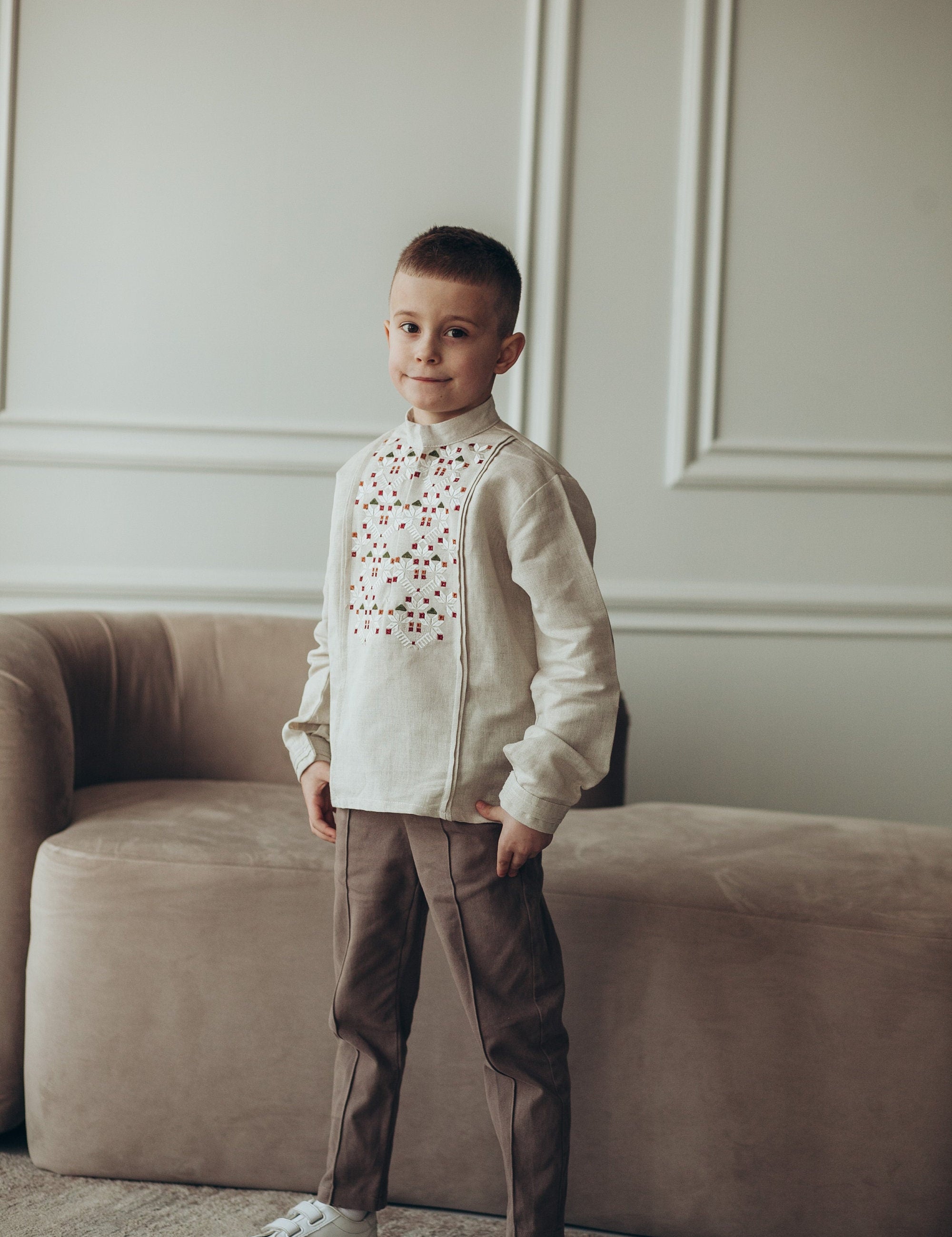 Boy wearing traditional Ukrainian embroidered linen shirt with long sleeves in a stylish setting.