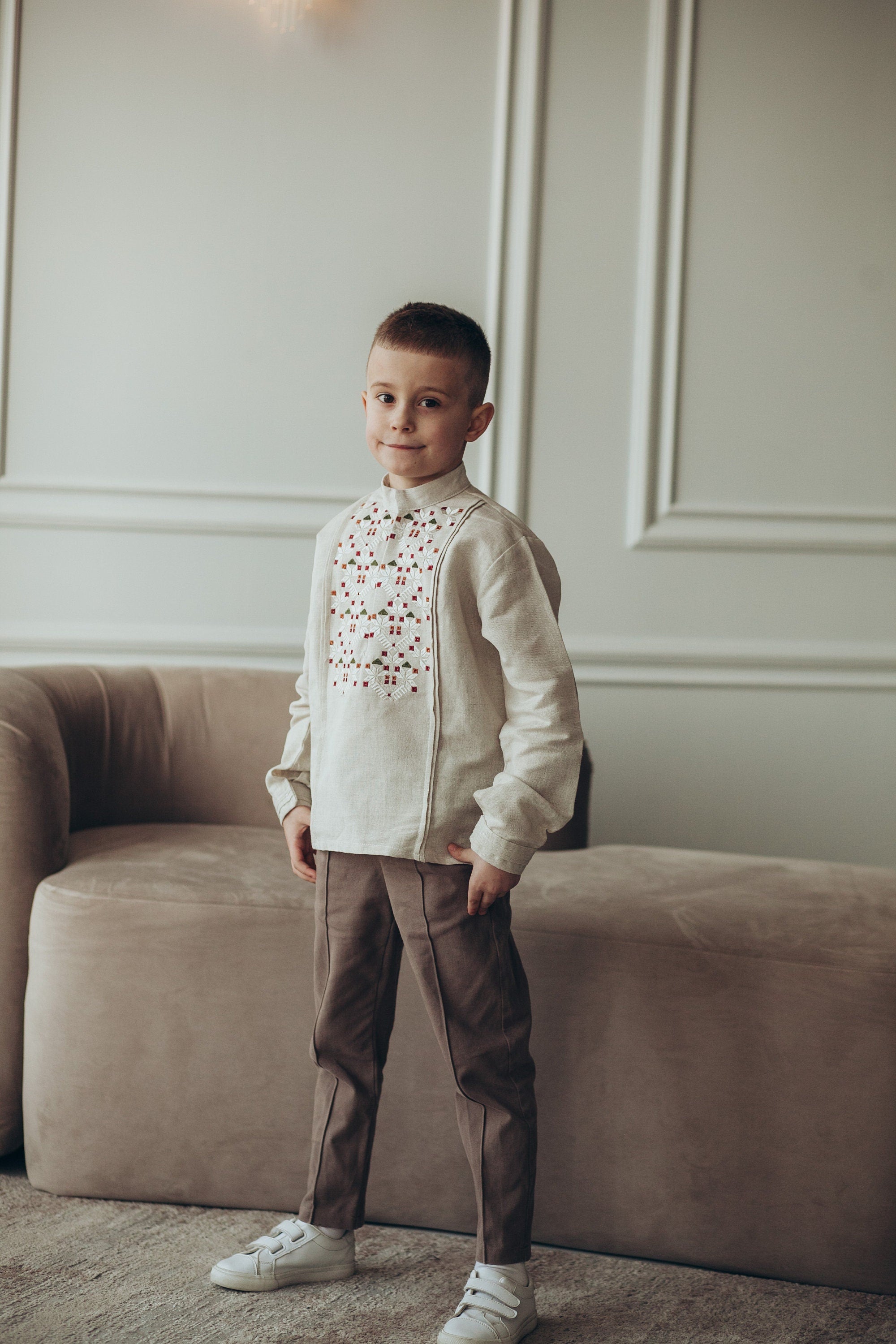 Boy wearing traditional Ukrainian embroidered linen shirt with long sleeves in a stylish setting.
