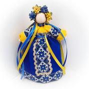 Ukrainian Motanka doll with blue and yellow dress, decorated with floral wreath, representing home protection and housewarming gift.
