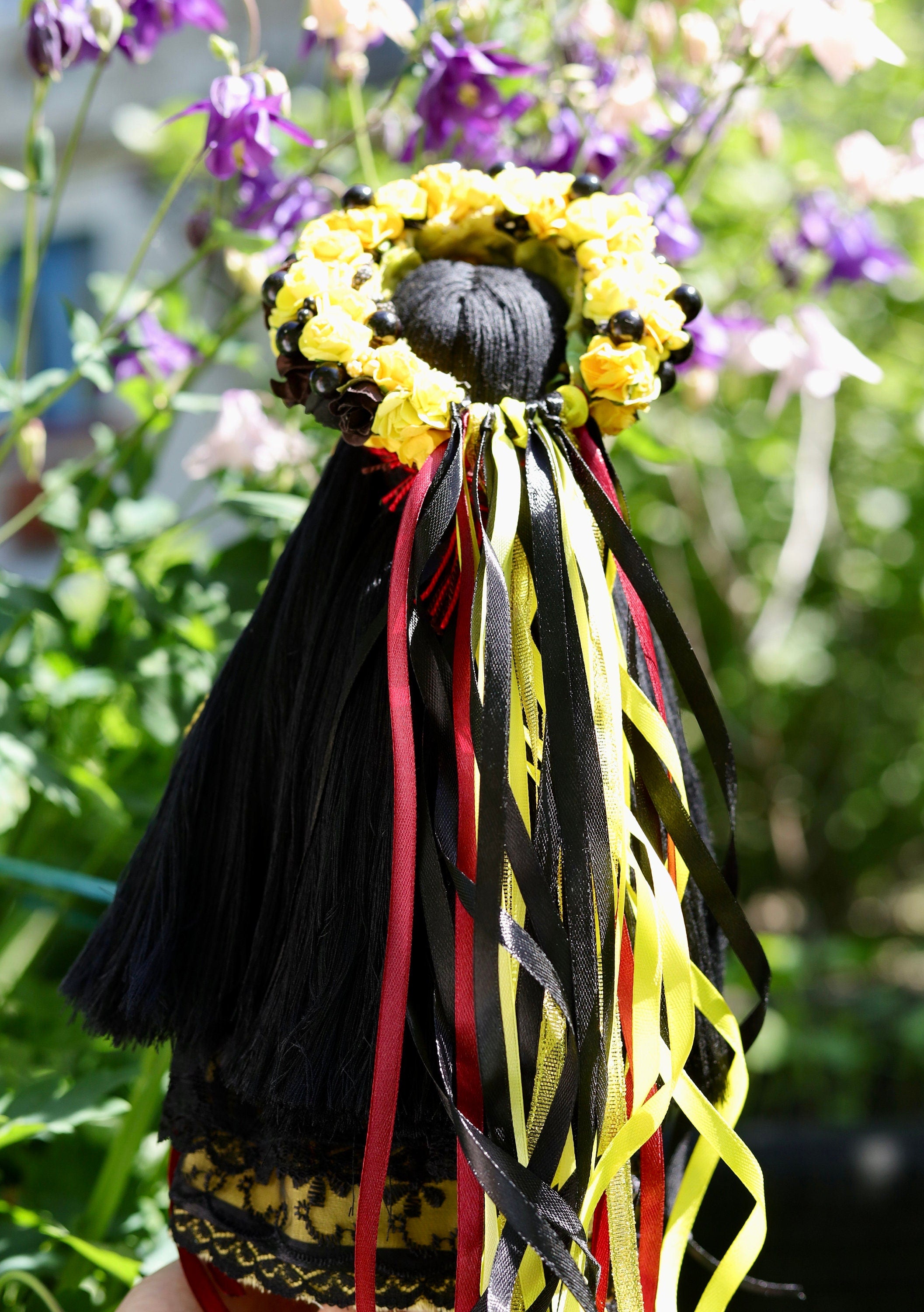 Handmade Ukrainian Motanka Doll with colorful ribbons and floral wreath in garden setting, symbolizing Slavic folklore and protection.