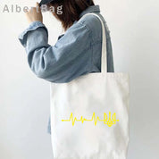 Ukrainian Patriotic Grocery Tote Bag with yellow heartbeat design carried by woman in denim shirt. Eco-friendly and reusable.