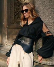 Woman wearing black-on-black embroidered Ukrainian blouse with tulle inserts, showcasing boho ethnic style against a rustic backdrop.
