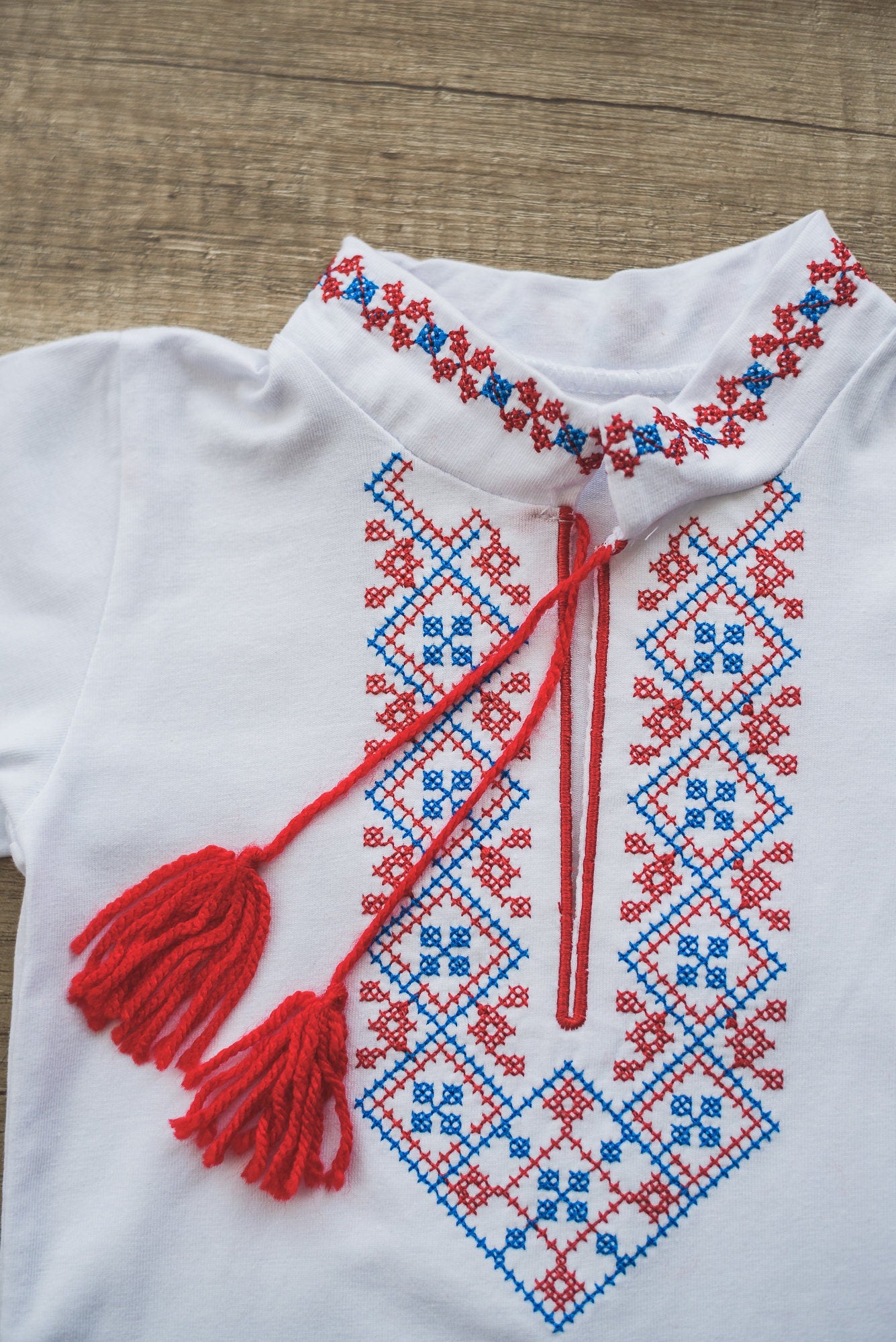 Ukrainian vyshyvanka for boys with red and blue embroidery, stand-up collar, and tassels, suitable for babies and toddlers.