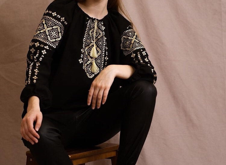 Woman wearing handmade embroidered blouse in boho ethno style with intricate Ukrainian Vyshyvanka design.