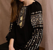 Woman wearing a handmade black embroidered blouse in boho ethno style with intricate Ukrainian Vyshyvanka designs.