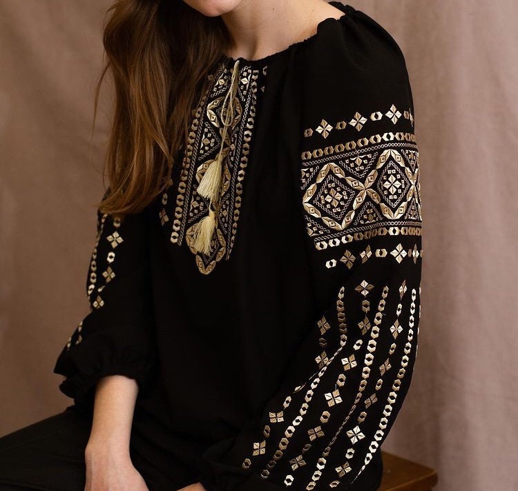 Woman wearing a handmade black embroidered blouse in boho ethno style with intricate Ukrainian Vyshyvanka designs.