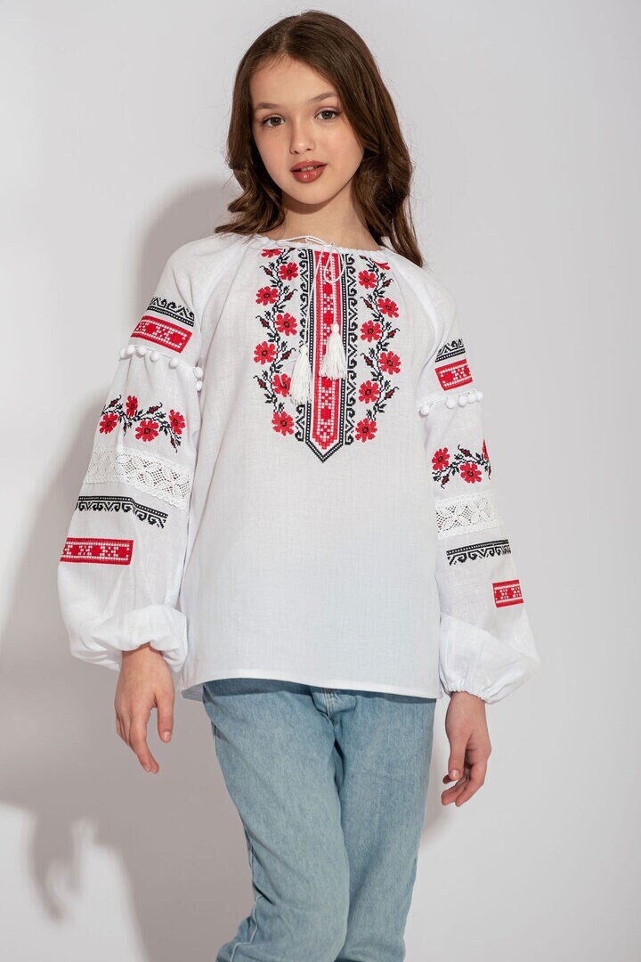 Child wearing Ukrainian white vyshyvanka shirt with red embroidery, showcasing folk design.