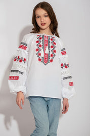 Child wearing Ukrainian white vyshyvanka shirt with red embroidery, showcasing folk design.