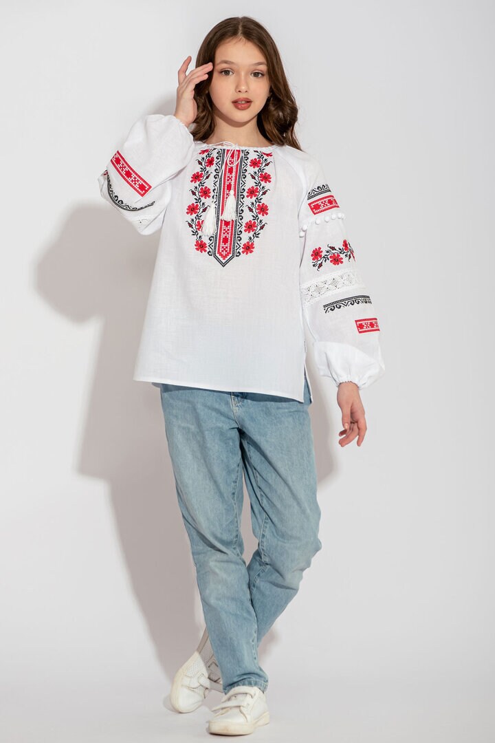 Ukrainian white children's vyshyvanka shirt with traditional embroidery worn by girl in casual jeans and sneakers.