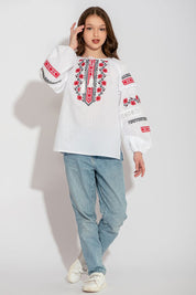 Ukrainian white children's vyshyvanka shirt with traditional embroidery worn by girl in casual jeans and sneakers.