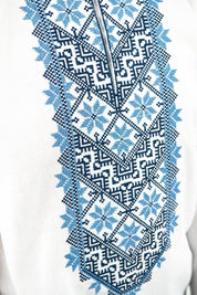 Close-up of blue Ukrainian embroidery on a white linen shirt for boys, showcasing traditional ethnic patterns.