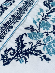 Close-up of traditional Ukrainian embroidery in blue cross-stitch patterns on a vyshyvanka fabric, showcasing intricate details.
