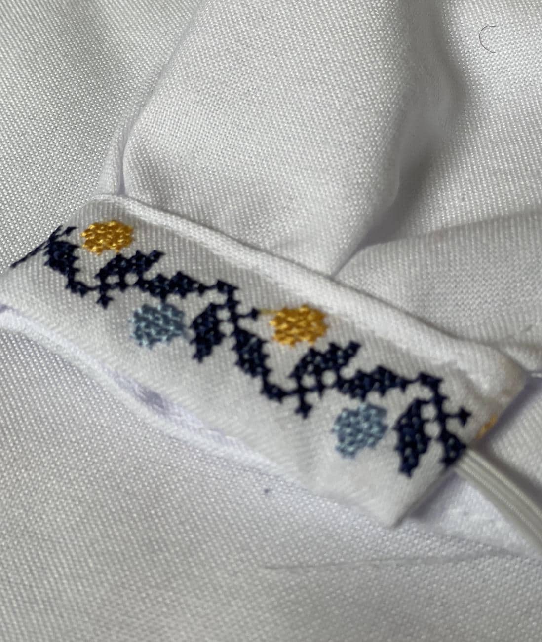 Close-up of Ukrainian boy's vyshyvanka shirt with blue and yellow Tryzub embroidery detail on high-quality cotton fabric.