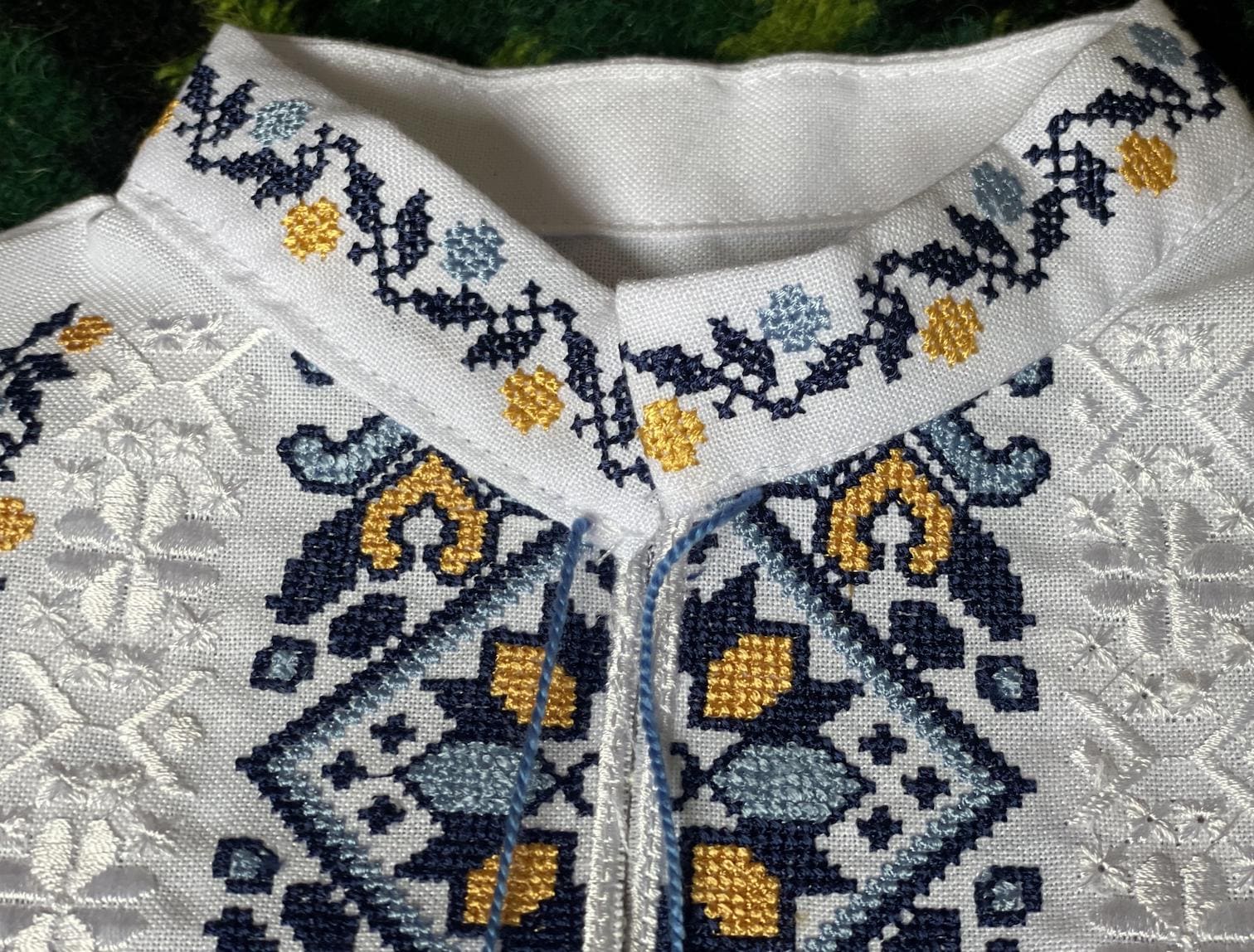 Close-up of Ukrainian boy's vyshyvanka shirt with blue and yellow Tryzub embroidery.