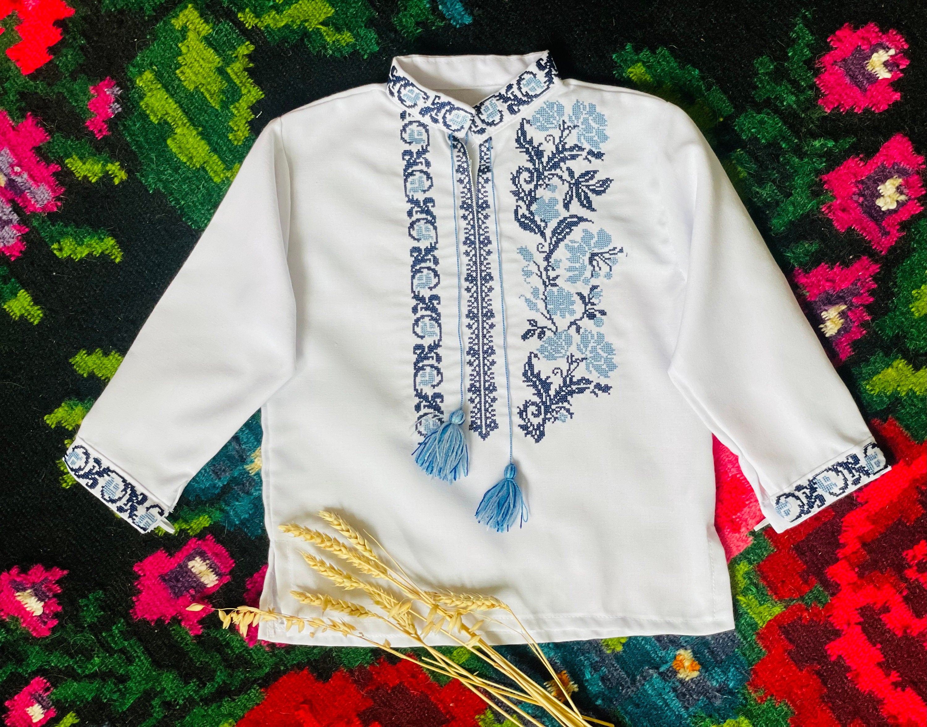 Embroidered Ukrainian boy's vyshyvanka shirt on patterned fabric background