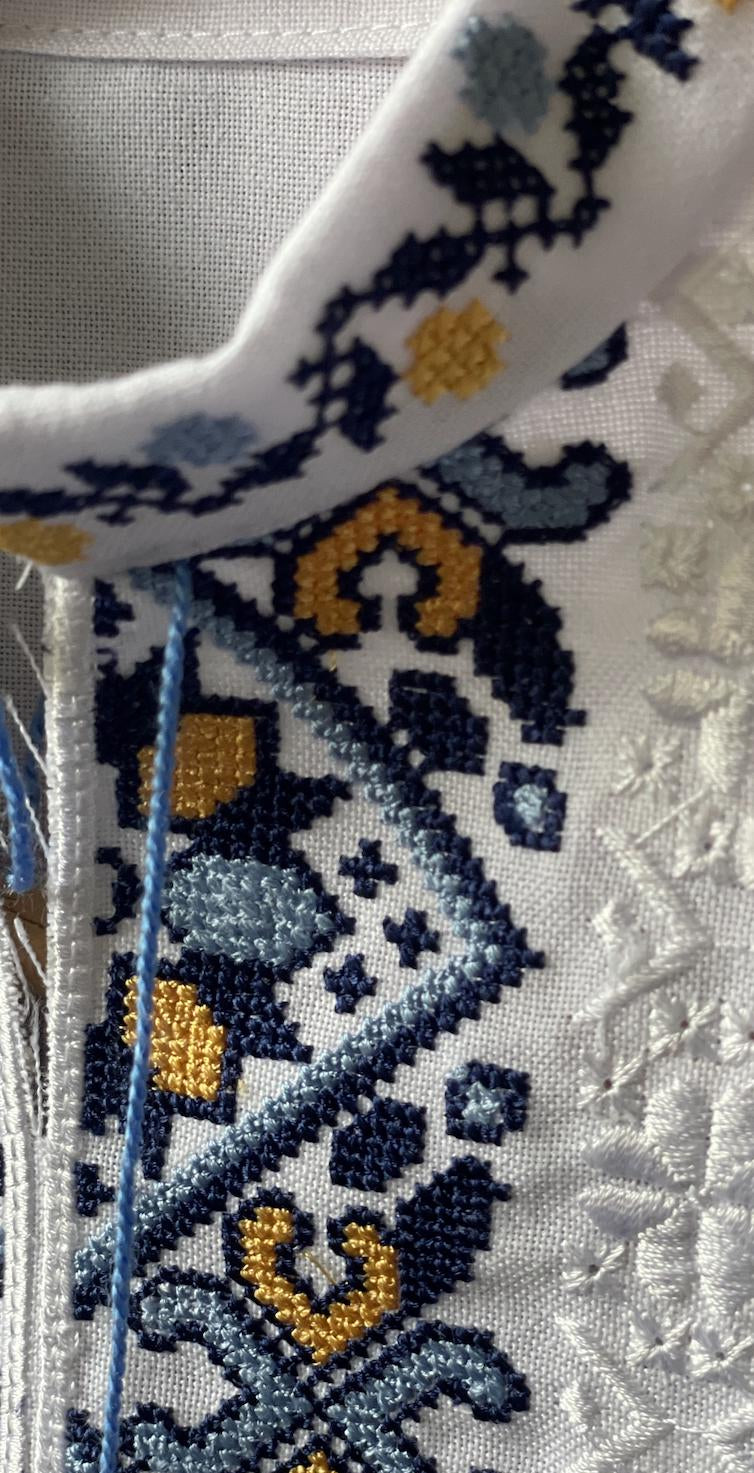 Close-up of Ukrainian embroidered boy's vyshyvanka shirt with blue and yellow Tryzub design, showcasing cultural heritage.
