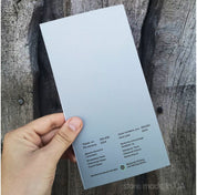 Hand holding the back of a Ukraine commemorative banknote booklet against a wooden background.