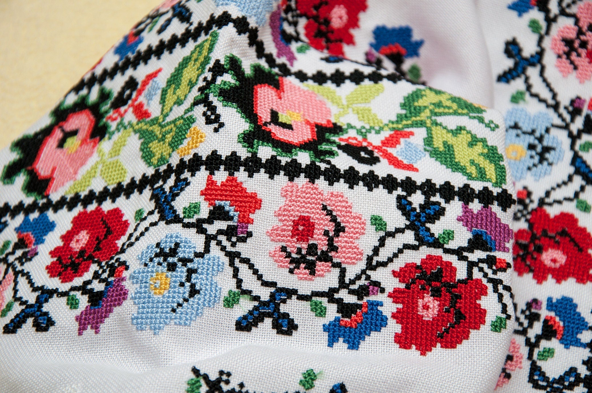 Detail of colorful floral cross-stitch on a Ukrainian embroidered blouse, showcasing traditional Vyshyvanka design.