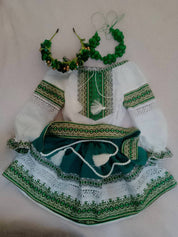 Traditional Ukrainian green and white embroidered blouse and skirt set for girls with matching floral accessories.