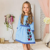 Young girl wearing a Ukrainian embroidered dress with floral details, traditional blue vyshyvanka design, suitable for cultural events.