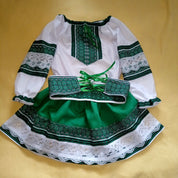 Girl's green and white embroidered Ukrainian blouse and skirt set featuring traditional patterns on a yellow background.