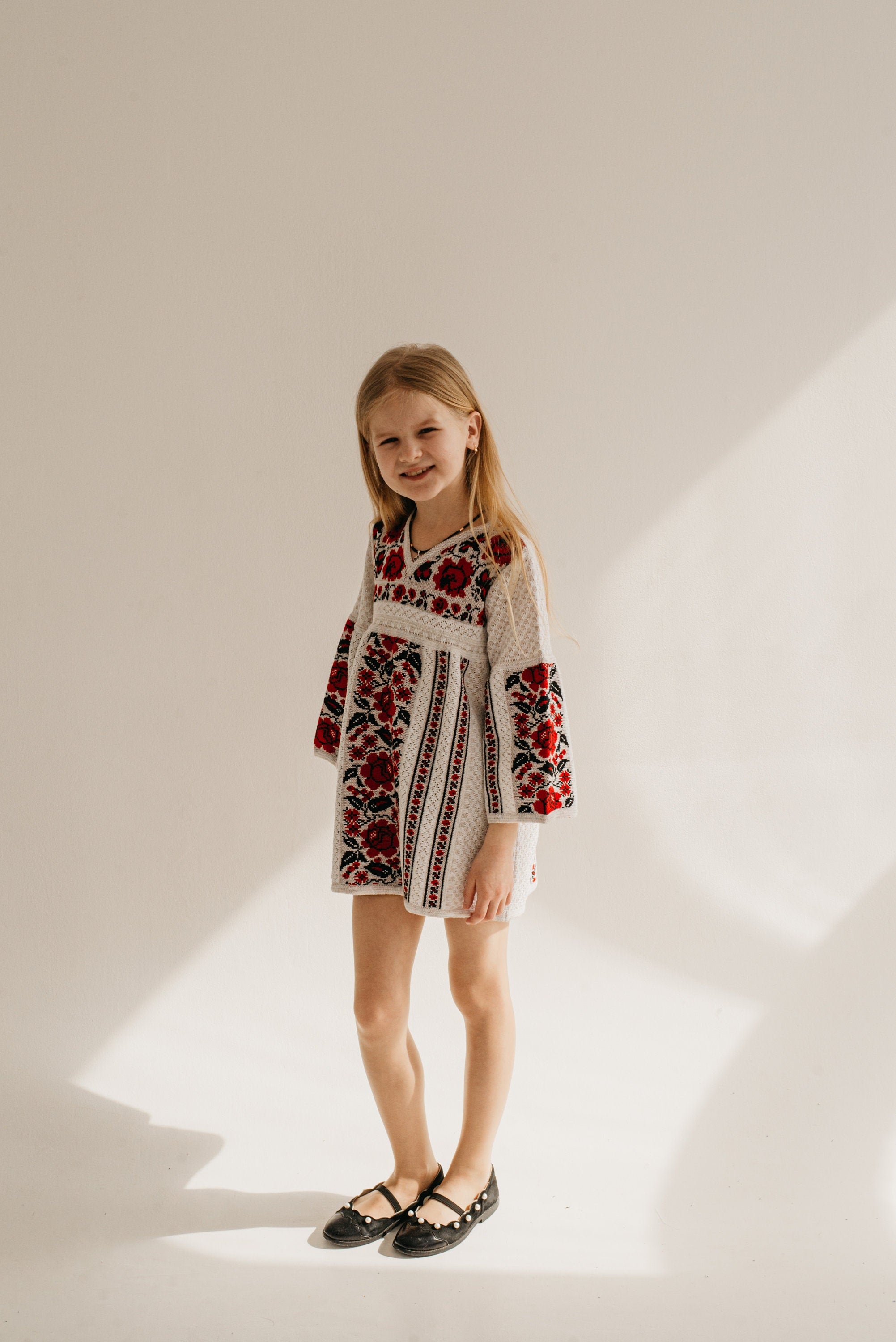 Girl wearing Ukrainian embroidered knit dress in traditional Vyshyvanka style, perfect cotton clothing gift for children.