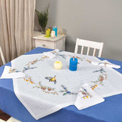 Embroidered linen tablecloth set with peony floral design, 90x90 cm, includes 4 napkins, displayed on a dining table with candles.