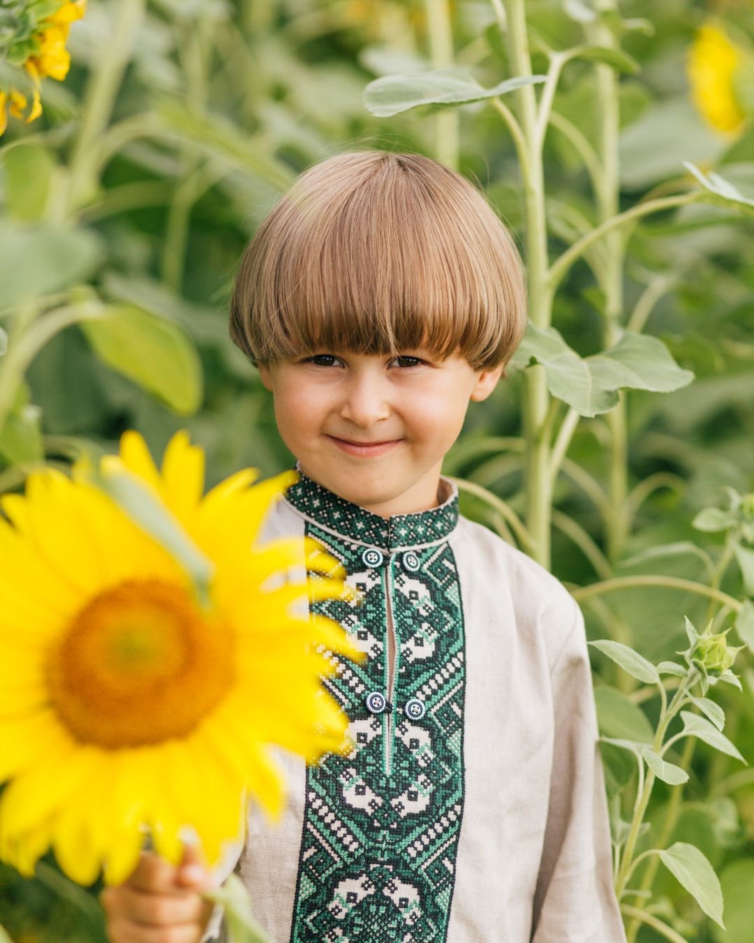 Boy wearing Ukrainian embroidered shirt vyshyvanka in sunflower field