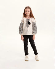 Girl wearing Ukrainian embroidered vyshyvanka shirt with Slavic folk art design, black and white patterns, cultural clothing