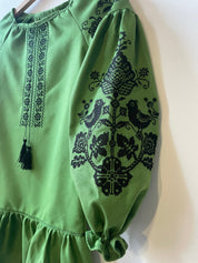 Green Ukrainian Vyshyvanka dress with black embroidered birds and flowers, featuring traditional cross-stitching.