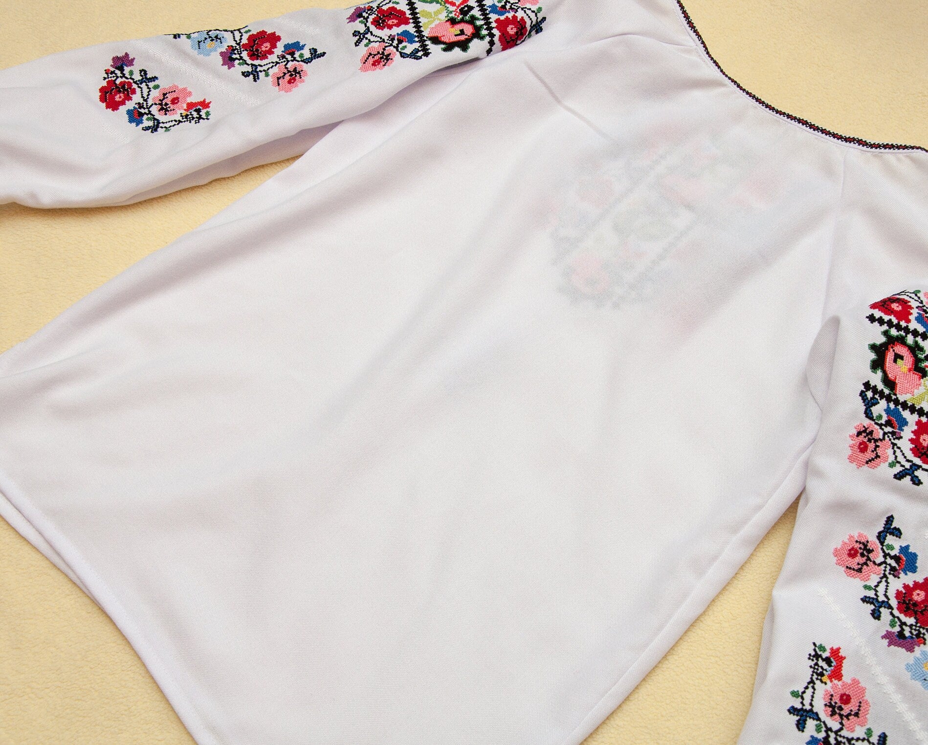 Traditional Ukrainian embroidered blouse for girls with floral design, showcasing vibrant cross-stitch on homespun fabric.