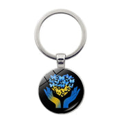 Ukrainian glass keychain with blue and yellow emblem design, symbolizing heritage and pride.