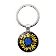 Ukrainian glass keychain with sunflower emblem, symbolizing heritage and pride.