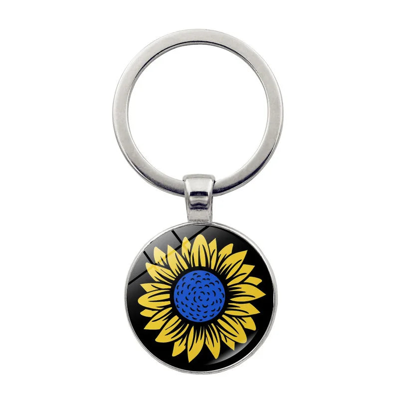 Ukrainian glass keychain with sunflower emblem, symbolizing heritage and pride.