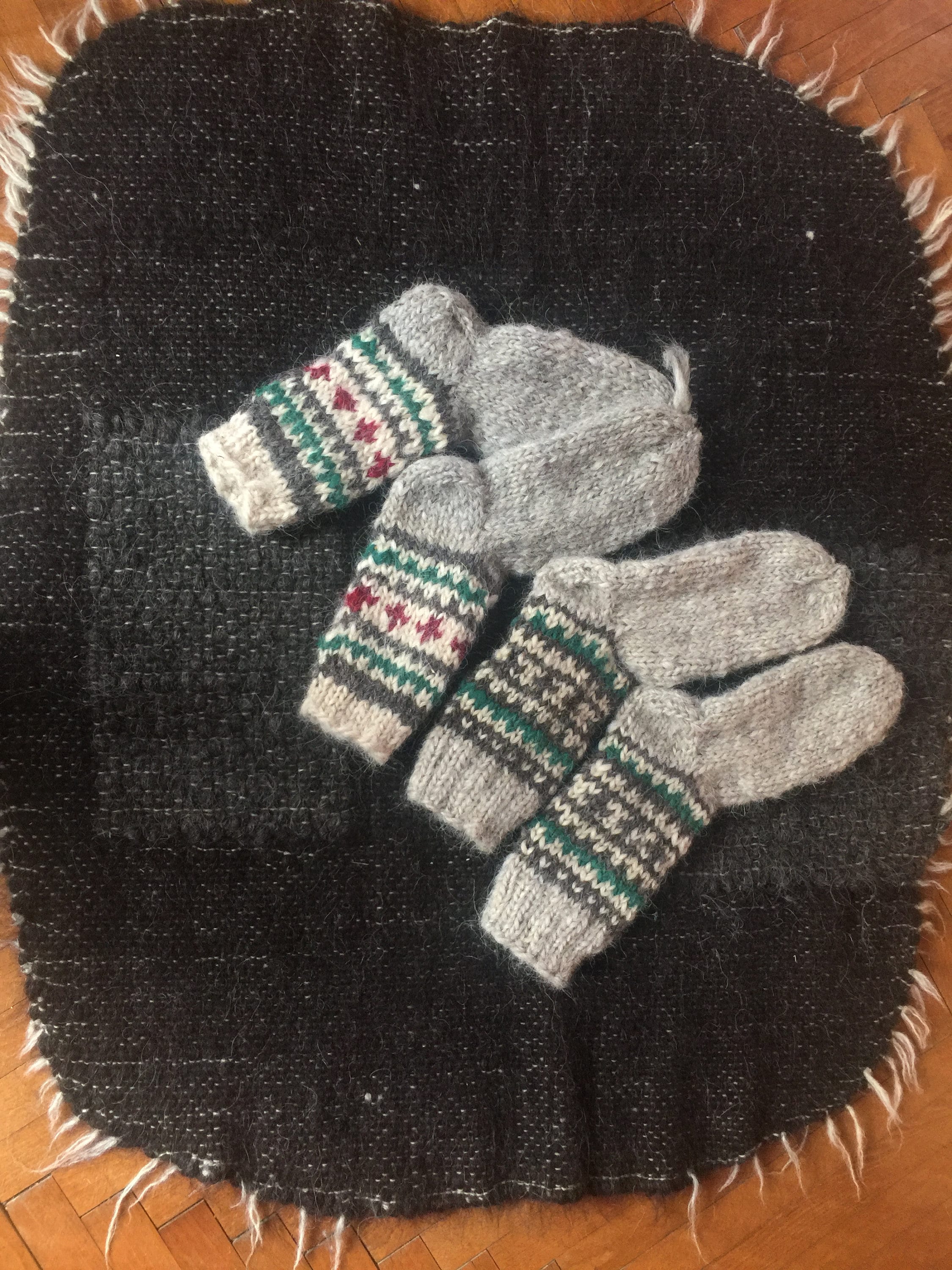 Hand-knitted wool socks with traditional patterns, made in Ukraine, displayed on a woven black cloth.