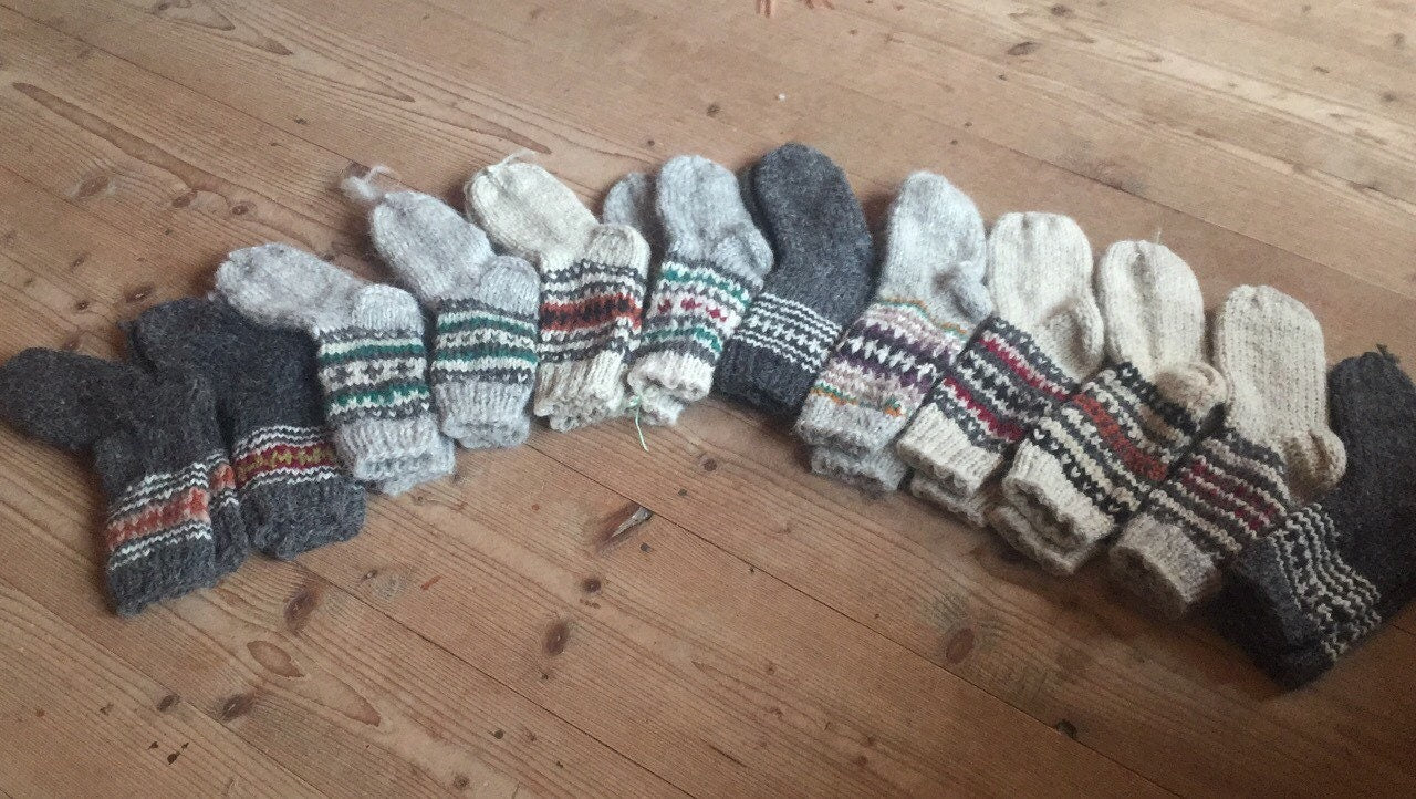 Array of handmade wool socks with colorful patterns laid on wooden floor.
