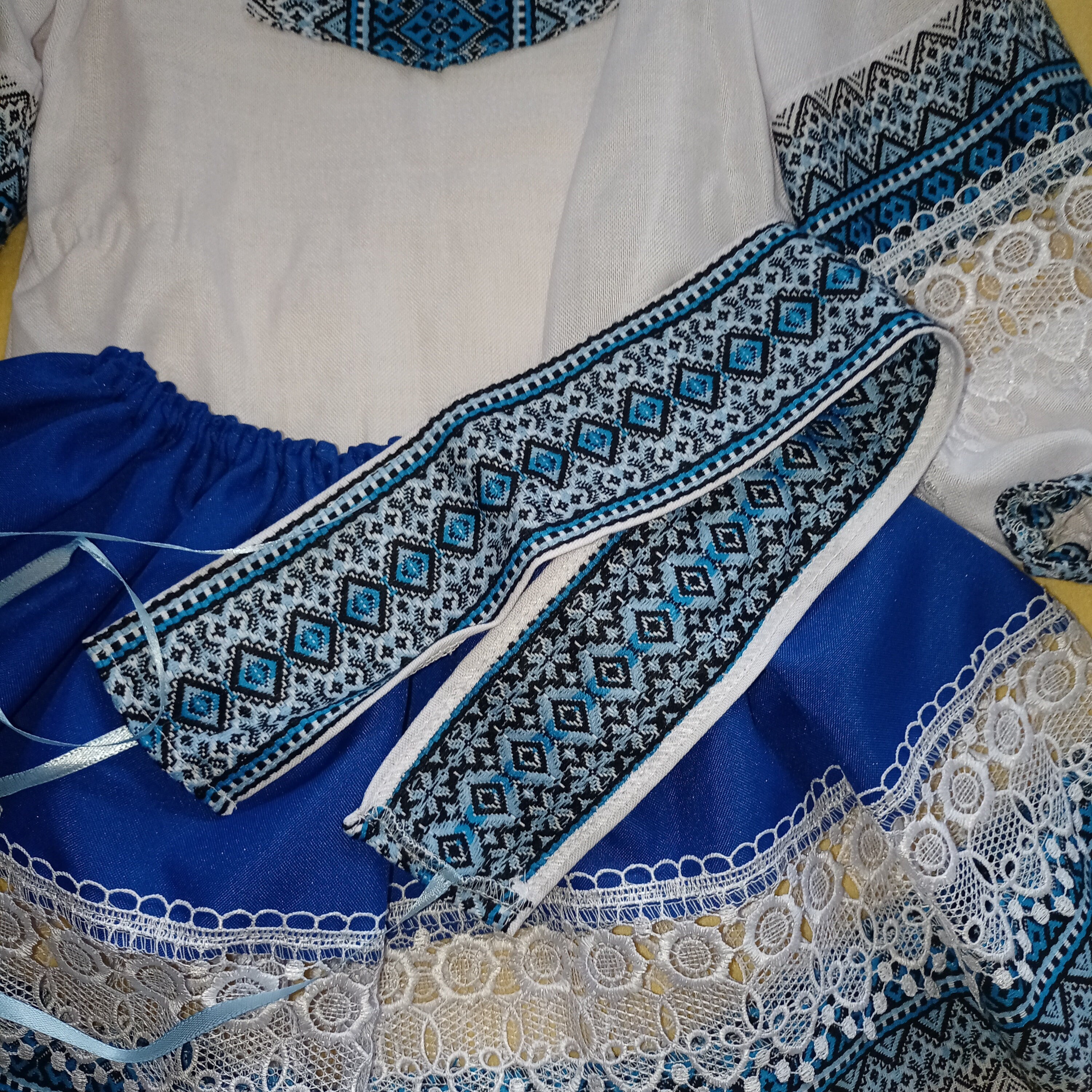 Ukrainian Hutsul folk costume for girls, featuring a blue woven blouse, lace skirt, and decorative belt for cultural events.