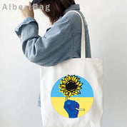 Eco-friendly Ukrainian Patriotic Grocery Tote Bag with sunflower design carried by a person in a denim jacket.