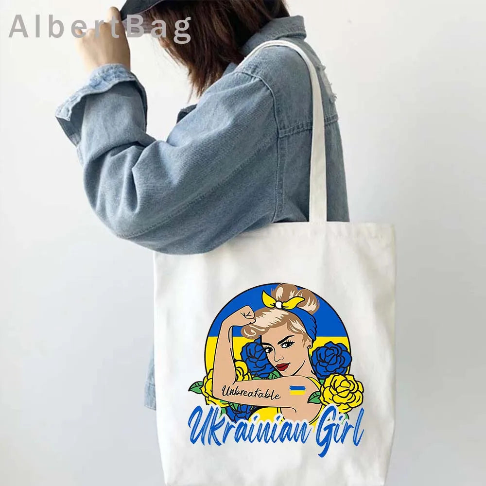 Woman holding Ukrainian Patriotic Grocery Tote Bag with "Unbreakable Ukrainian Girl" design in blue and yellow.