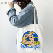 Woman holding Ukrainian Patriotic Grocery Tote Bag with "Unbreakable Ukrainian Girl" design in blue and yellow.
