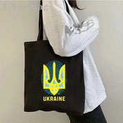 Person holding Ukrainian Patriotic Grocery Tote Bag with eco-friendly cotton fabric and stylish yellow trident design.
