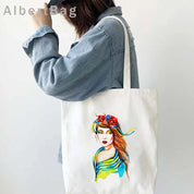 Woman carrying Ukrainian patriotic grocery tote bag with colorful print design.