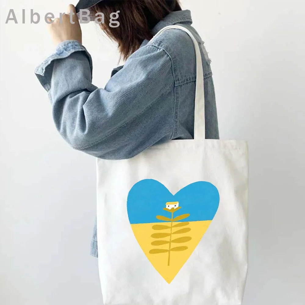 Woman with Ukrainian patriotic grocery tote bag featuring heart design, eco-friendly and reusable cotton fabric.