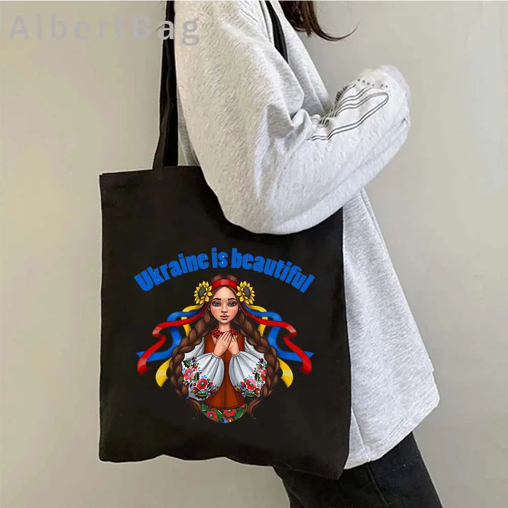 Ukrainian patriotic grocery tote bag with "Ukraine is beautiful" design, worn over shoulder.