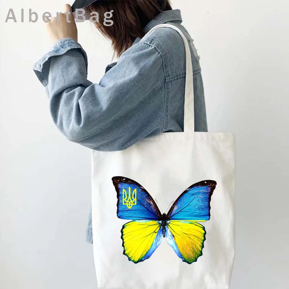 Woman holding Ukrainian Patriotic Grocery Tote Bag with butterfly design.